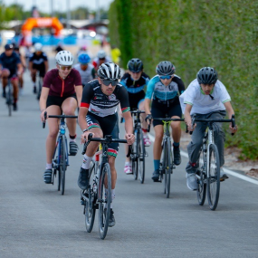 Cyclists in helmets race along a road